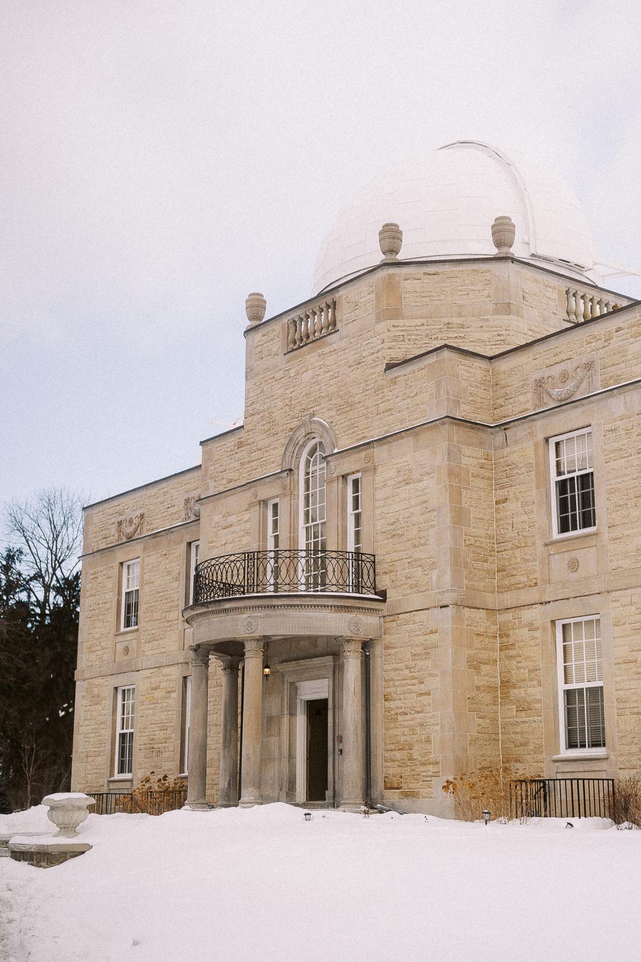 Historic stone observatory building with a domed roof, surrounded by a snowy landscape.