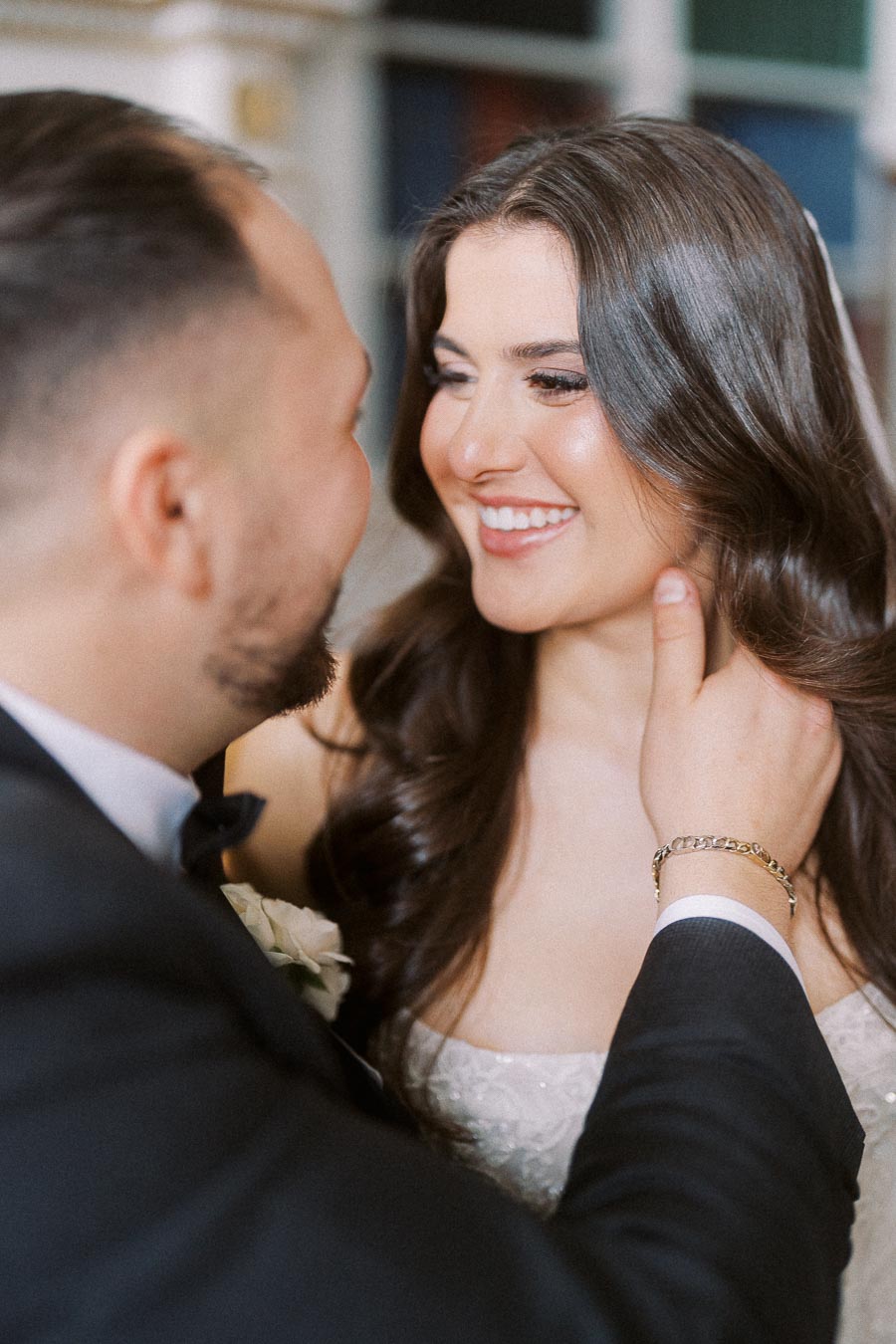 A happy couple gazing into each other's eyes during their wedding day, with the groom gently holding the bride's face.