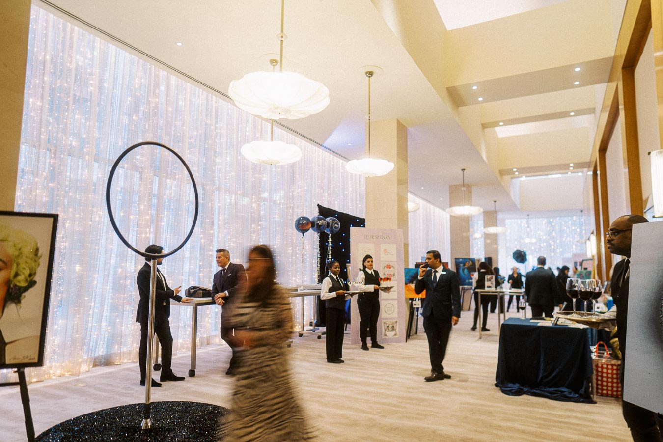Corporate networking event in a spacious, elegantly decorated venue with attendees in formal attire engaging in conversation and networking. The room features ambient lighting and modern decor, creating a sophisticated and professional atmosphere.