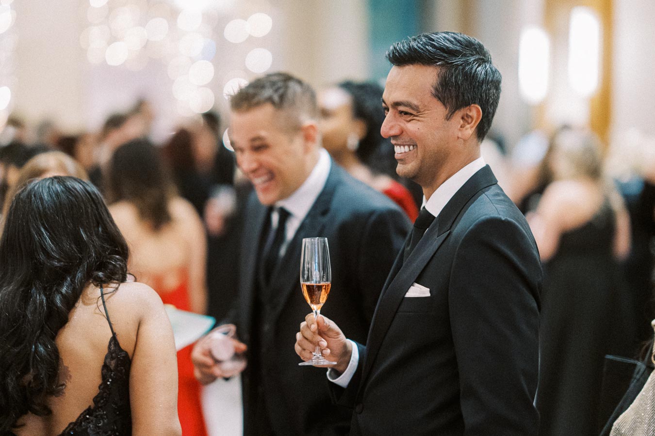 Formal event attendees enjoy socializing and champagne in an elegant setting.