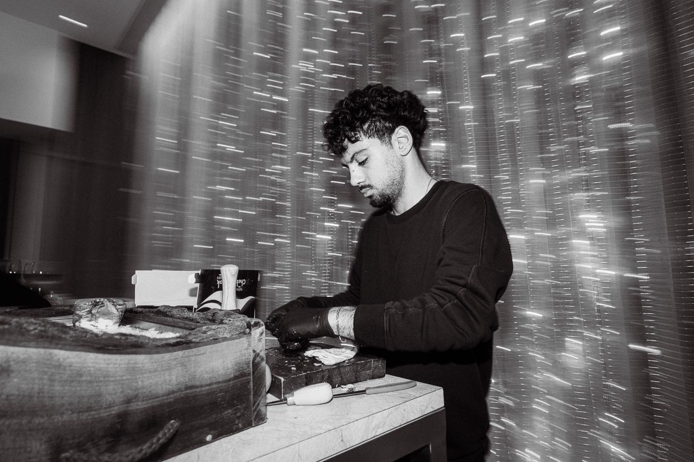 A chef meticulously preparing food at a stylish restaurant, set against a shimmering curtain backdrop.