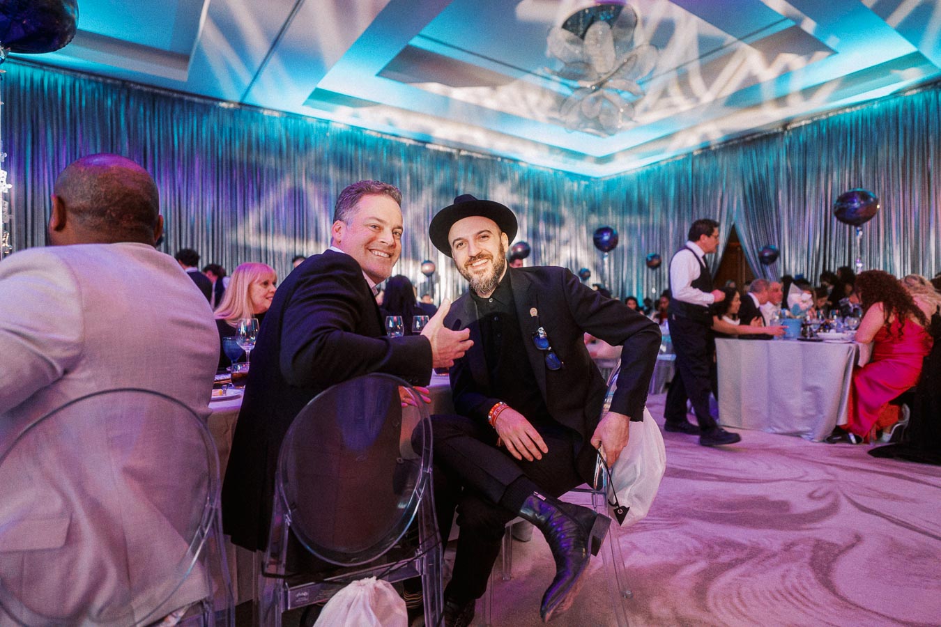 Guests enjoying a formal gathering in an elegantly decorated venue, featuring ambient lighting and sophisticated attire.