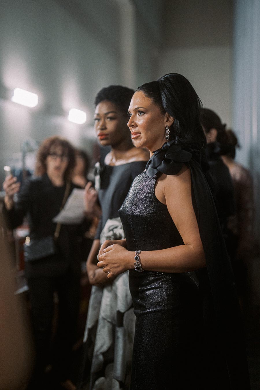 Elegant women in glamorous evening gowns at a fashion event, with focus on chic hairstyles and sophisticated jewelry, capturing the essence of high fashion and style.