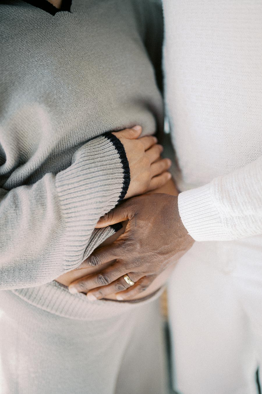 Hands of a couple gently embracing, symbolizing love and togetherness, wearing cozy knit sweaters.