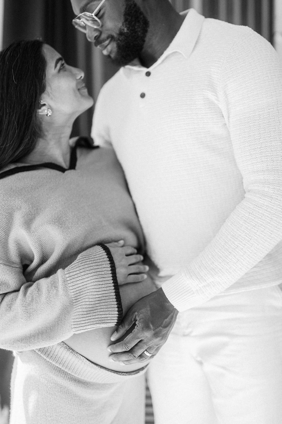 A couple lovingly embracing while the woman cradles her pregnant belly, capturing a tender moment of anticipation and joy.