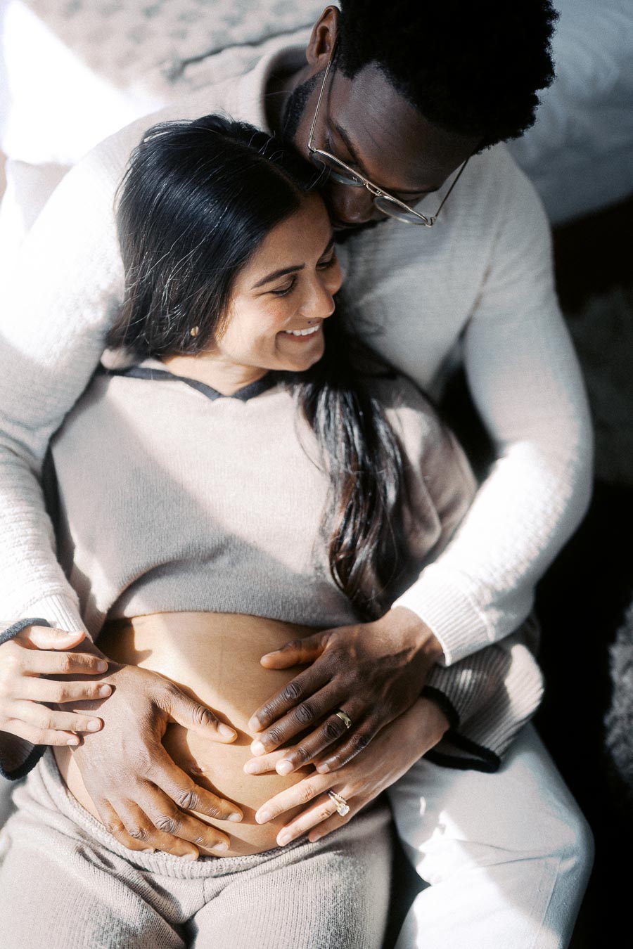 A loving couple embracing with hands on a pregnant belly, symbolizing expectant parenthood and family bonding.
