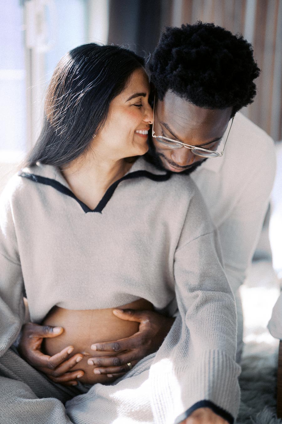 Loving couple sharing an intimate moment, with the man embracing his pregnant partner, highlighting their joy and anticipation of parenthood.