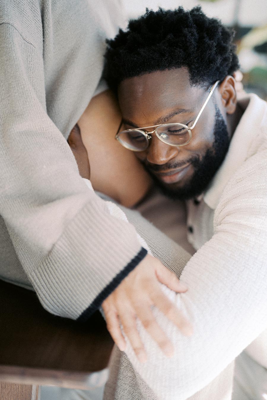 A man with glasses lovingly rests his head on his pregnant partner's belly while embracing her, capturing a tender moment of anticipation and connection.