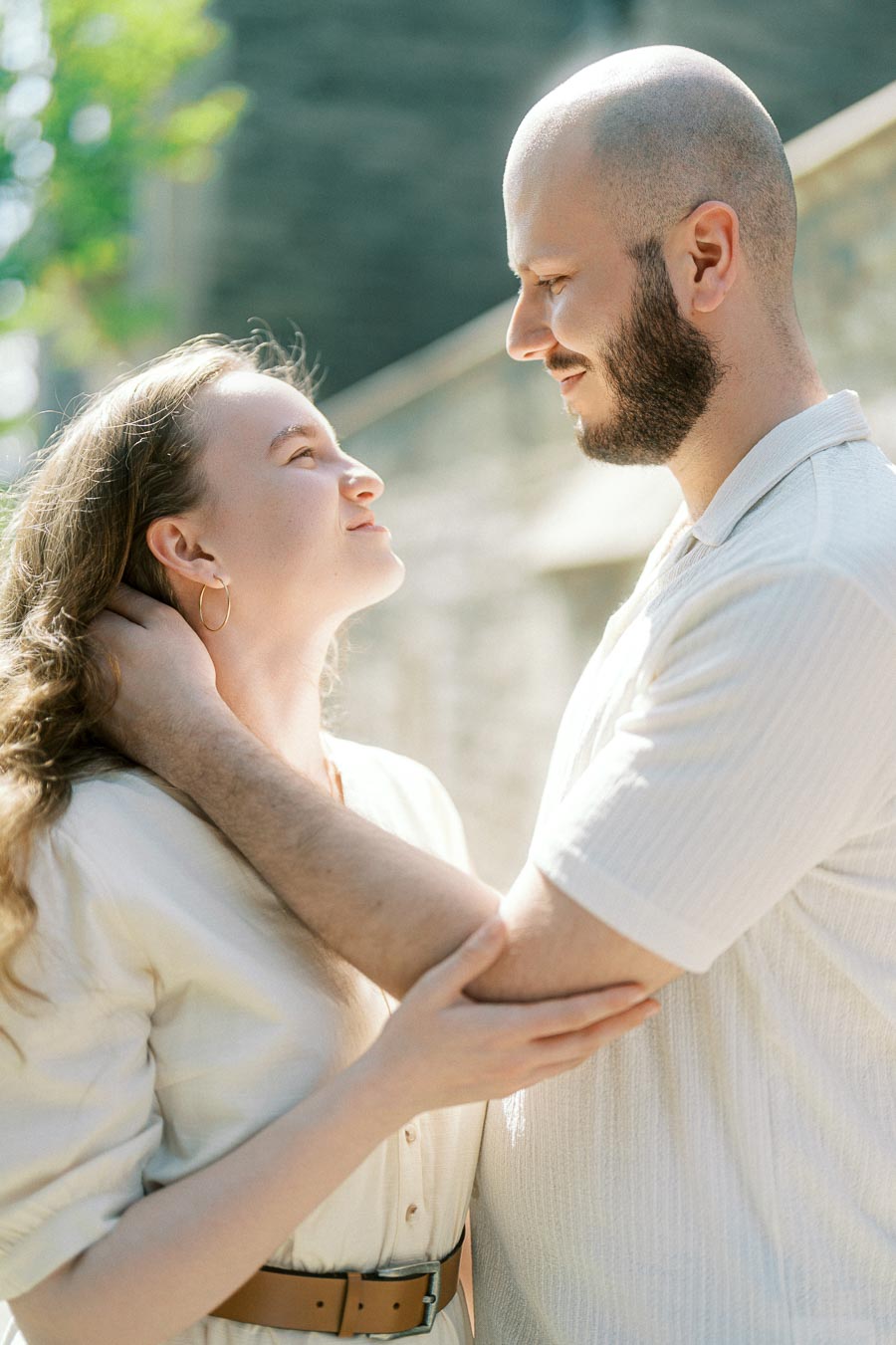 A couple gazes lovingly at each other, sharing a gentle embrace in bright spring light on the University of Toronto campus.