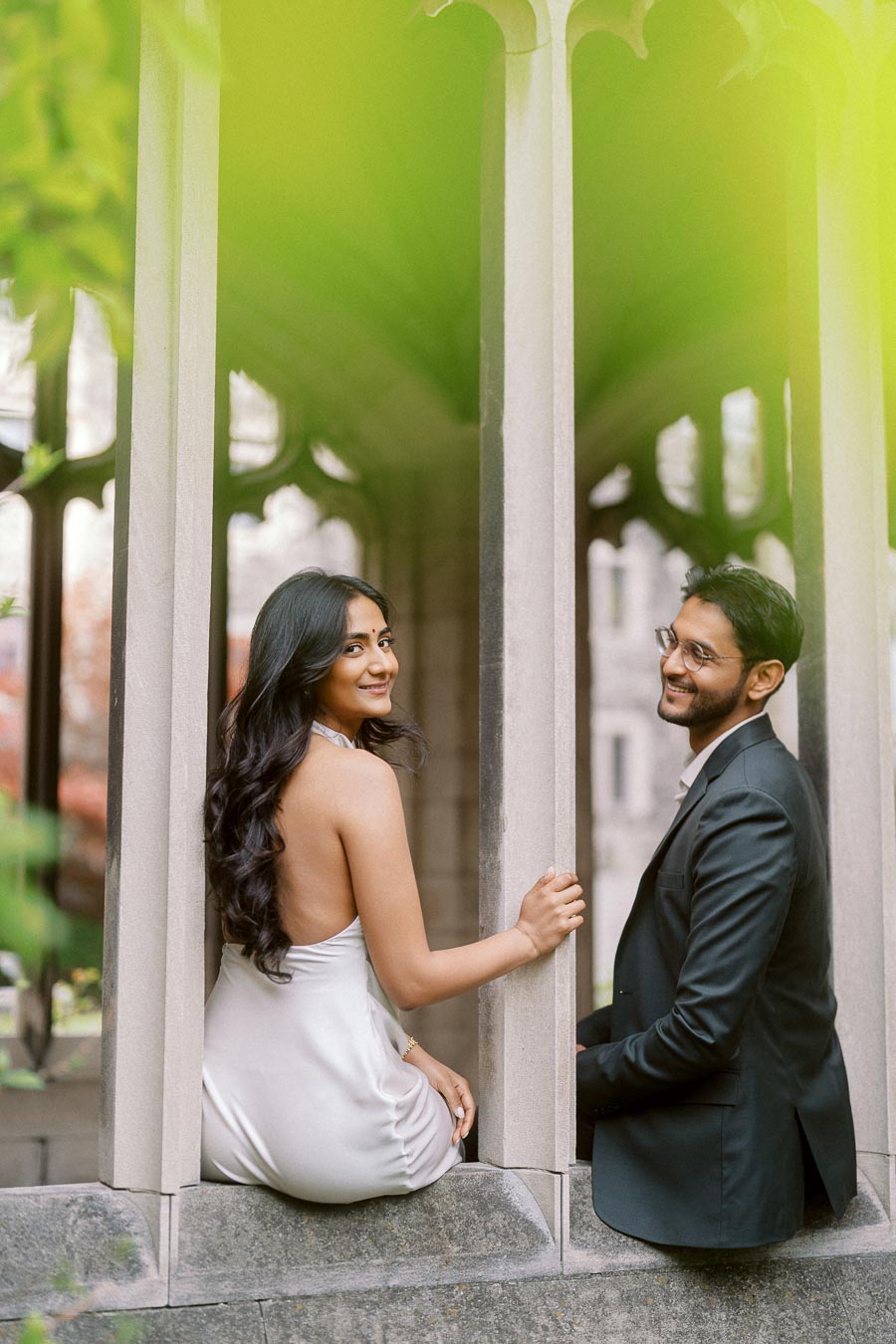 Tej and Priyana pose together within a stone archway at the University of Toronto, surrounded by soft greenery and historic architecture.