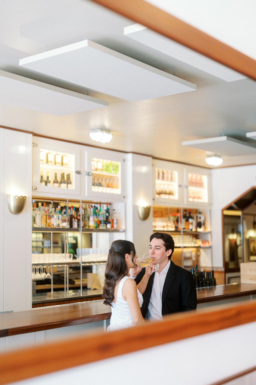 A couple enjoying drinks together at a modern bar in Ontario, Canada, sharing a romantic and joyful moment during their engagement photoshoot.