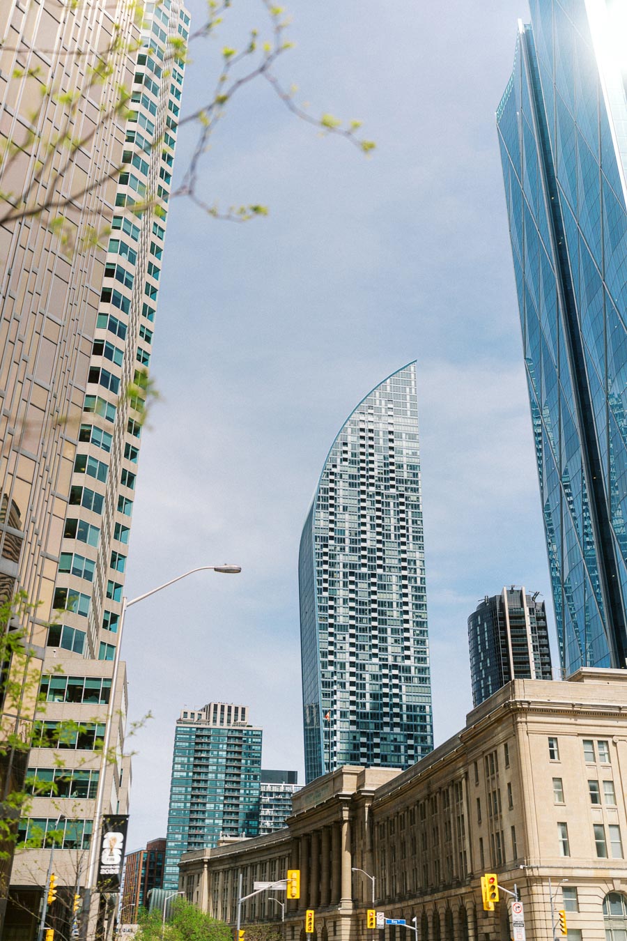 View of downtown Toronto with modern glass skyscrapers and historic Union Station building under a blue sky.