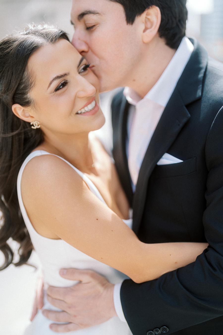 Close-up of a smiling couple embracing outdoors, with the man kissing the womans cheek during their engagement photoshoot.