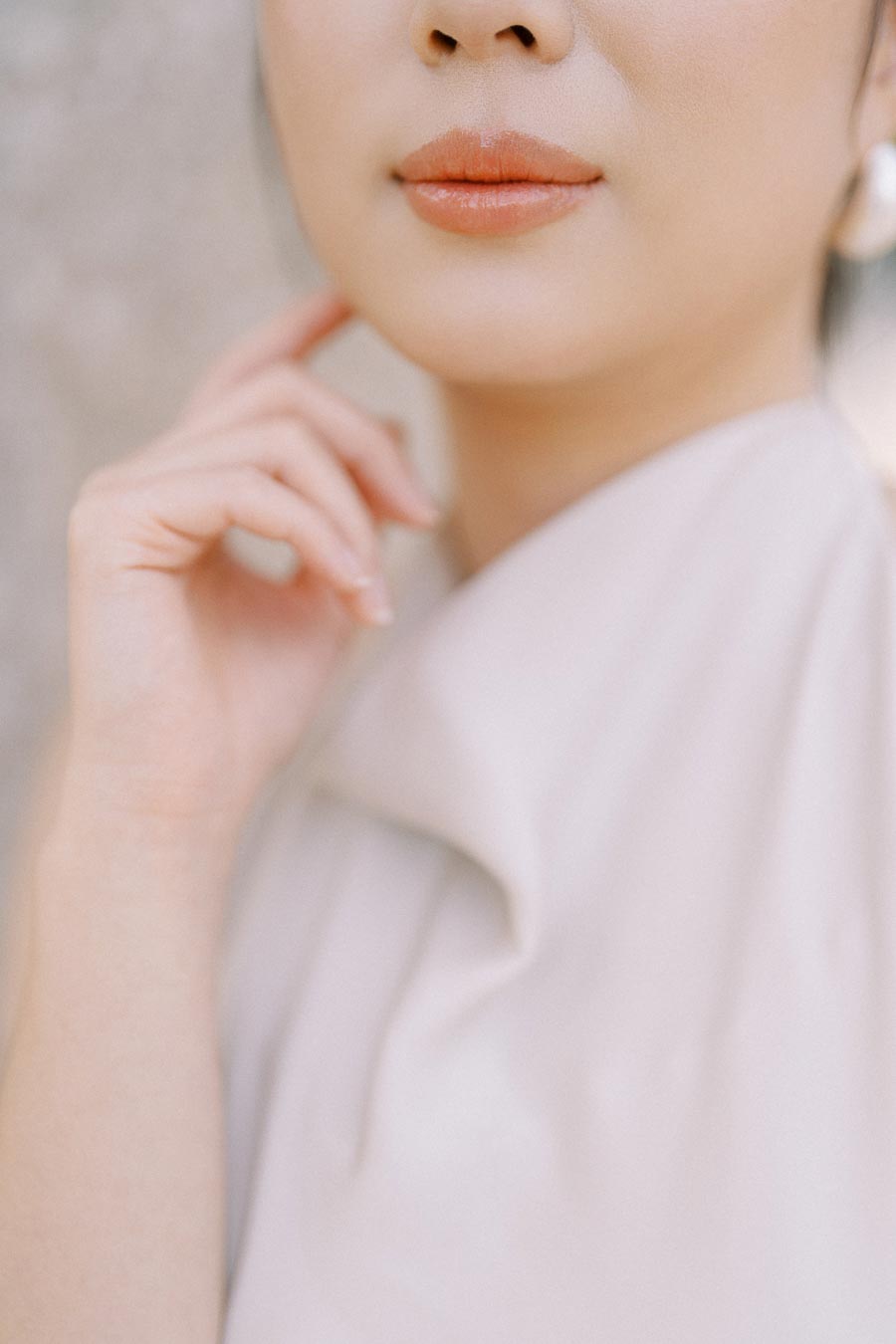 Close-up of an engaged woman's face and hand, highlighting her soft makeup, natural lips, and elegant white dress at Trillium Park, Toronto.
