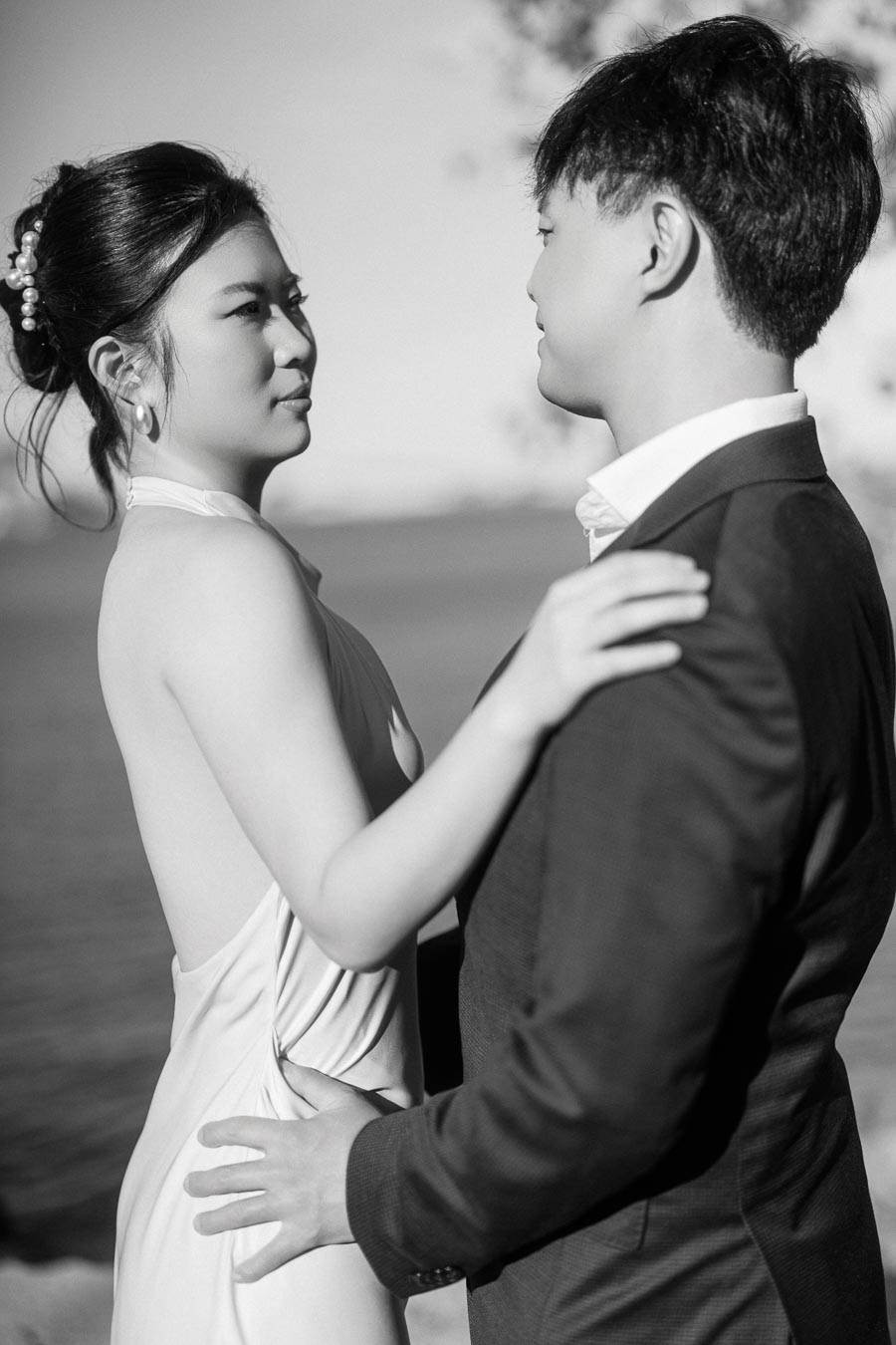 Engaged couple embracing closely in black and white, with the Toronto waterfront softly blurred in the background at Trillium Park.