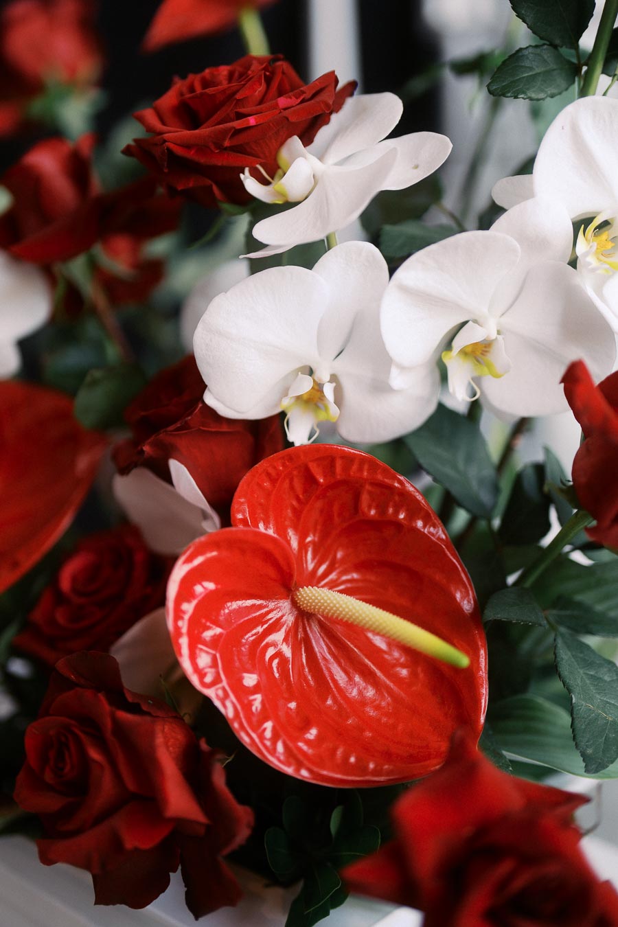 Close-up of red roses, white orchids, and red anthurium flowers in a floral arrangement at Ricarda’s Toronto event for screen readers.