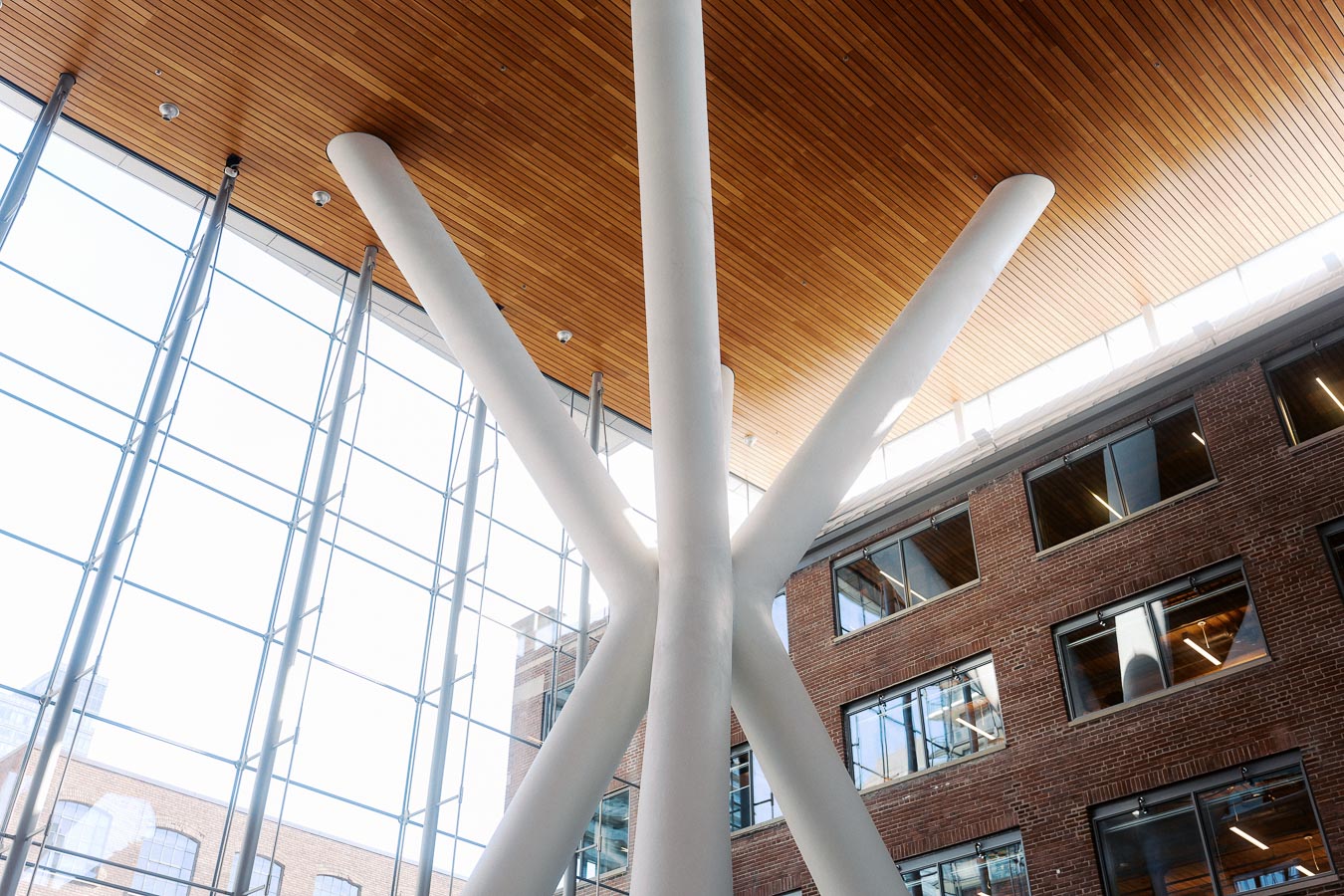 Interior view of Ricarda’s Atrium in Toronto with white structural columns, wood ceiling, large glass windows, and exposed brick walls, photographed at a school event.