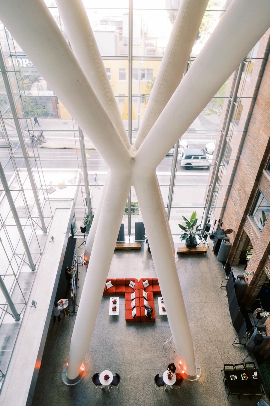 Overhead view of The Atrium at Ricarda’s in Toronto, featuring large white beams, glass walls, red lounge seating, and event tables set for the Toronto Prep Forever Launch Party.