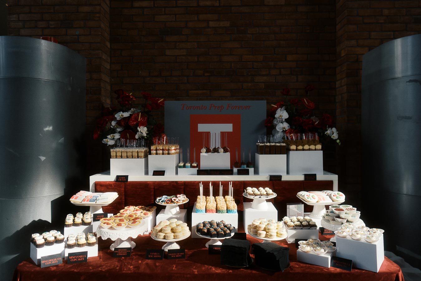 A dessert table with cupcakes, cake pops, macarons, and Toronto Prep School branding at Ricarda’s during the Toronto Prep Forever Launch Party.