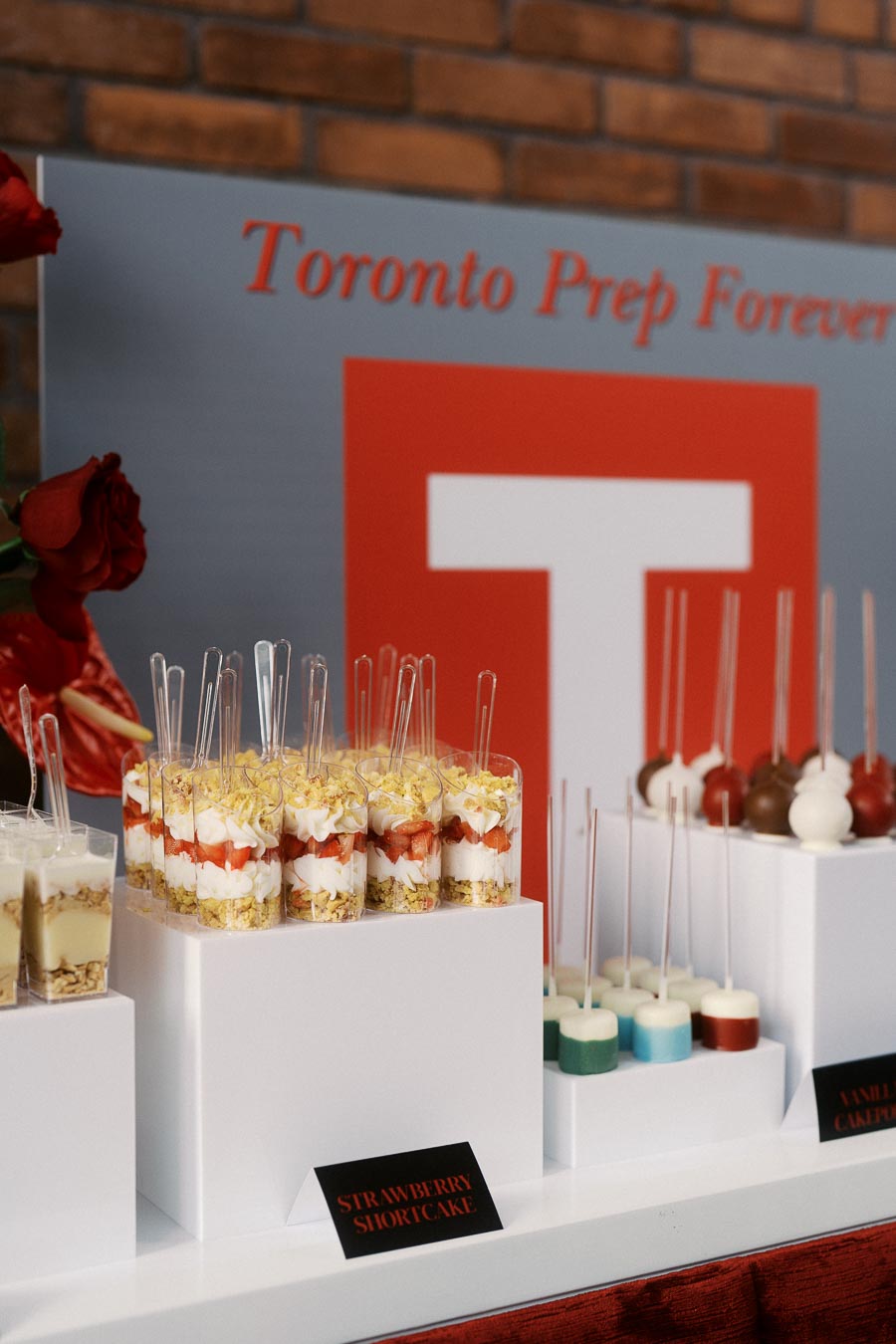 Dessert table with strawberry shortcake parfaits and colourful cake pops in front of Toronto Prep School signage at Ricarda’s, Toronto.