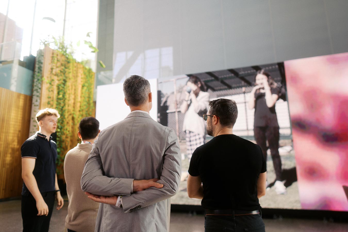 Group of people seen from behind watching a large digital screen presentation at Toronto Prep Forever Launch Party, Ricarda’s Atrium, Toronto.