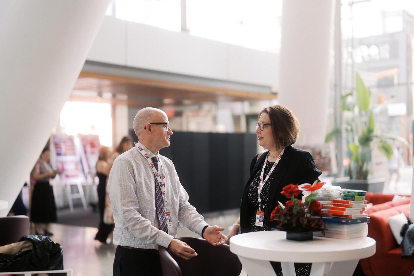 Two adults in business attire converse beside a round table with books and flowers at Ricarda’s during the Toronto Prep Forever Launch Party.