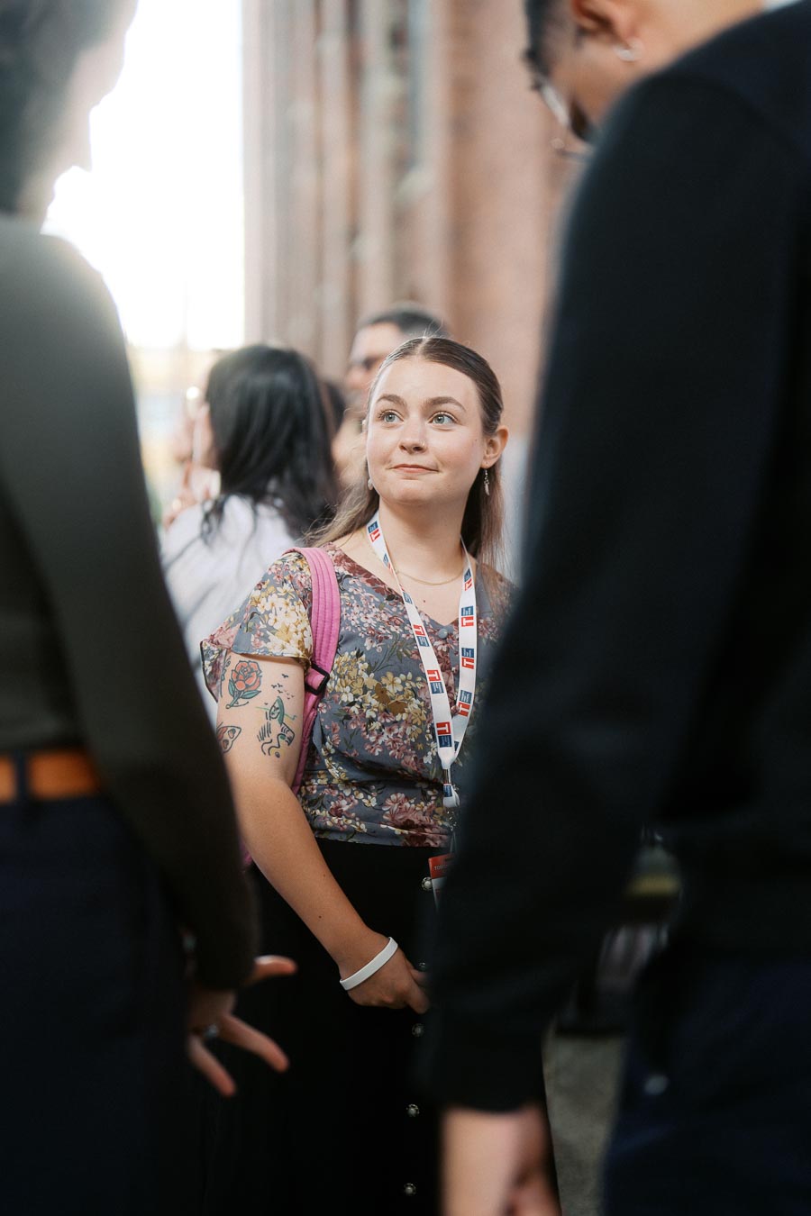 A woman wearing a Toronto Prep School lanyard and floral shirt stands among a group of people, engaged in conversation at Ricarda’s event space in Toronto.