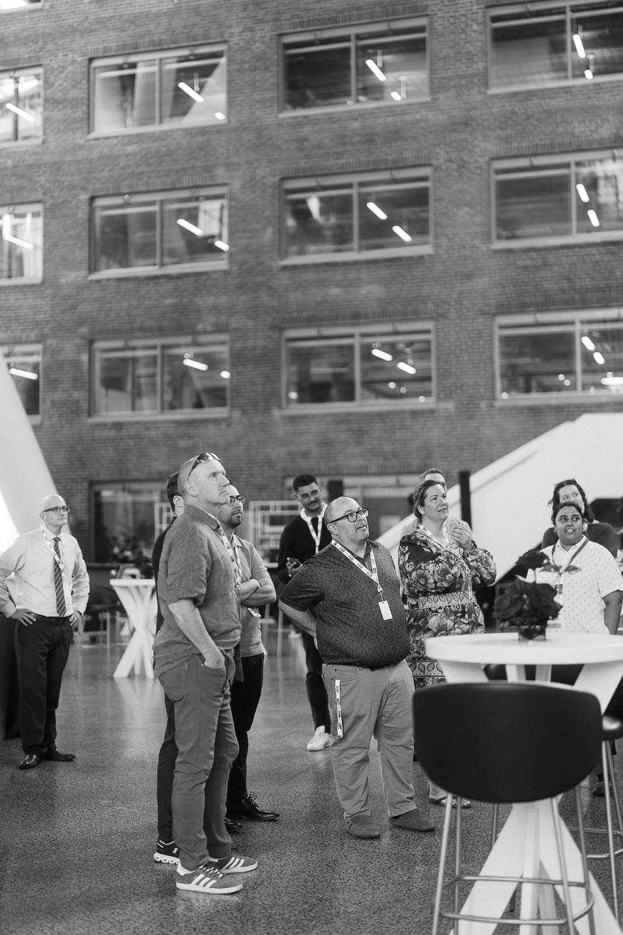 A group of adults stand together in conversation in the modern, brick-walled Atrium at Ricarda’s during the Toronto Prep Forever Launch Party.