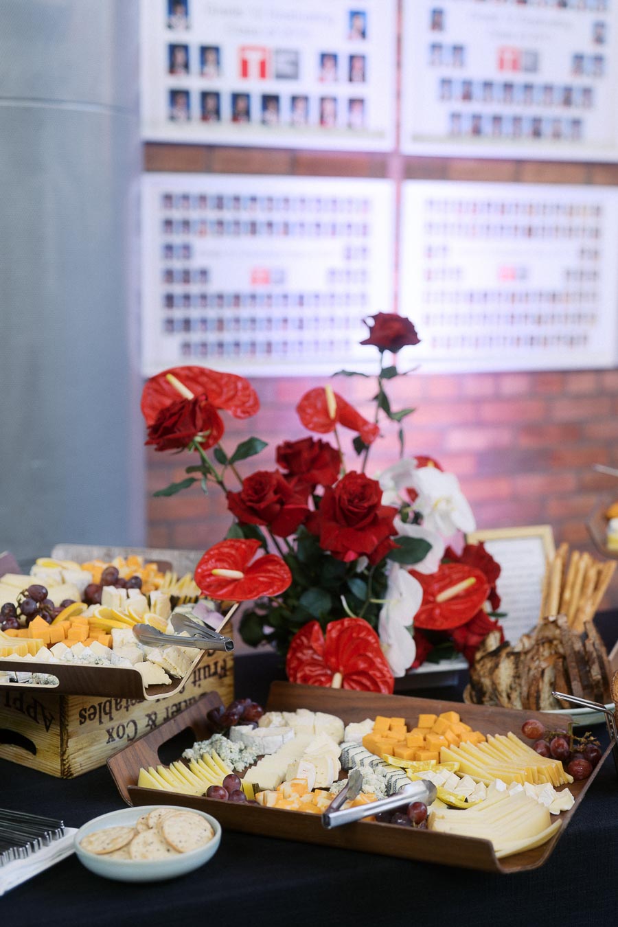 Cheese platters with grapes, crackers, and a red and white floral arrangement on a black tablecloth at Ricarda’s event space in Toronto.
