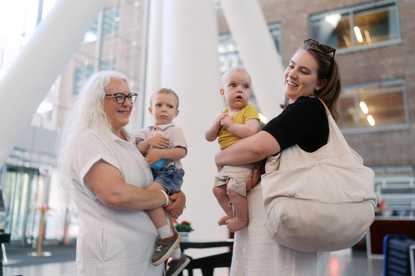 Two women holding young children stand together inside The Atrium at Ricarda’s, Toronto, during the Toronto Prep Forever Launch Party event.