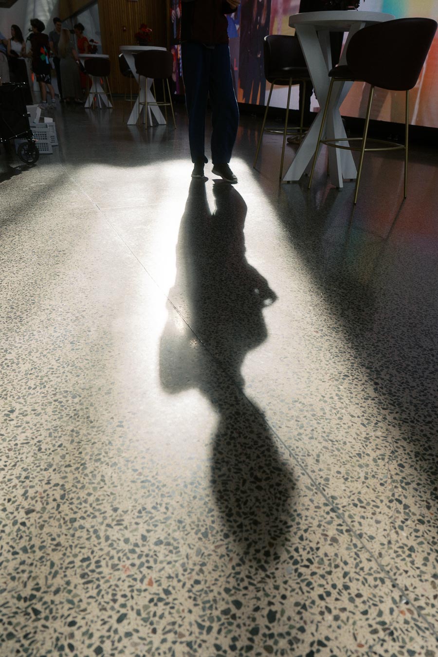 A guest's silhouette is dramatically cast on the terrazzo floor at Ricarda’s, with event tables and attendees in the background at the Toronto Prep School Forever Launch Party.