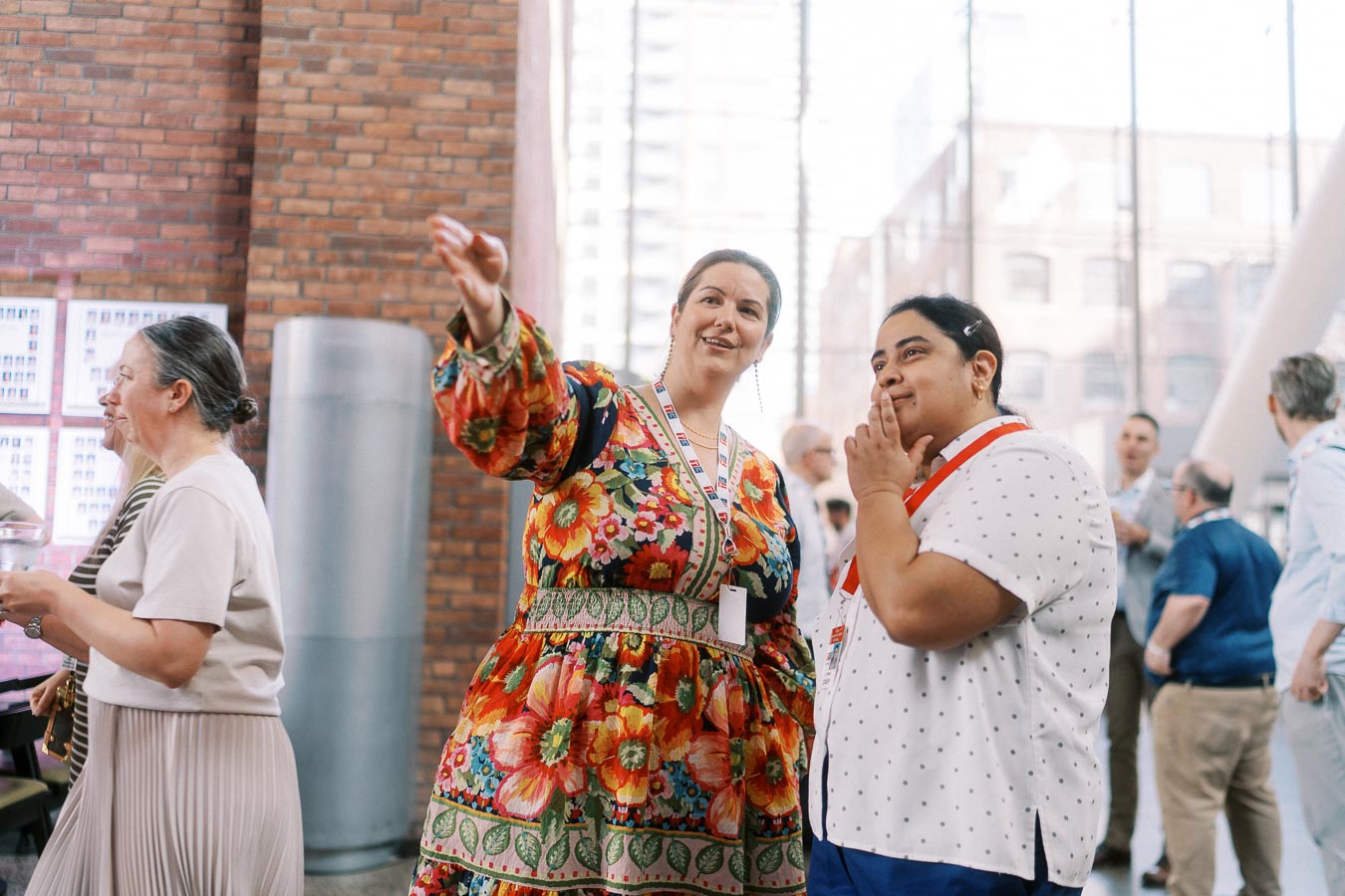 Two women converse and gesture while networking at the Toronto Prep Forever Launch Party inside Ricarda’s, with guests and modern brick interior in the background.