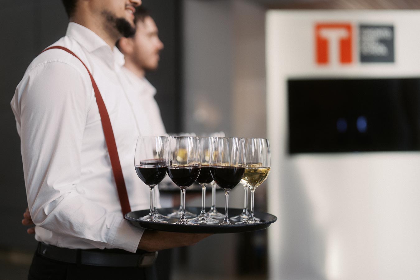 Server in white shirt with red suspenders holding a tray of red and white wine glasses at Toronto Prep School event at Ricarda’s, Toronto.