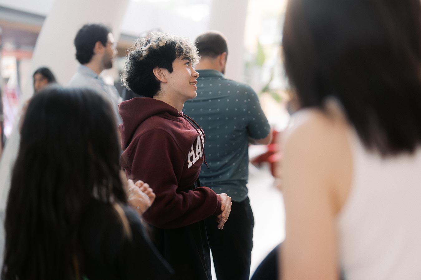 A group of guests, including a smiling youth in a maroon hoodie, socialize in the bright atrium during the Toronto Prep Forever Launch Party at Ricarda’s.
