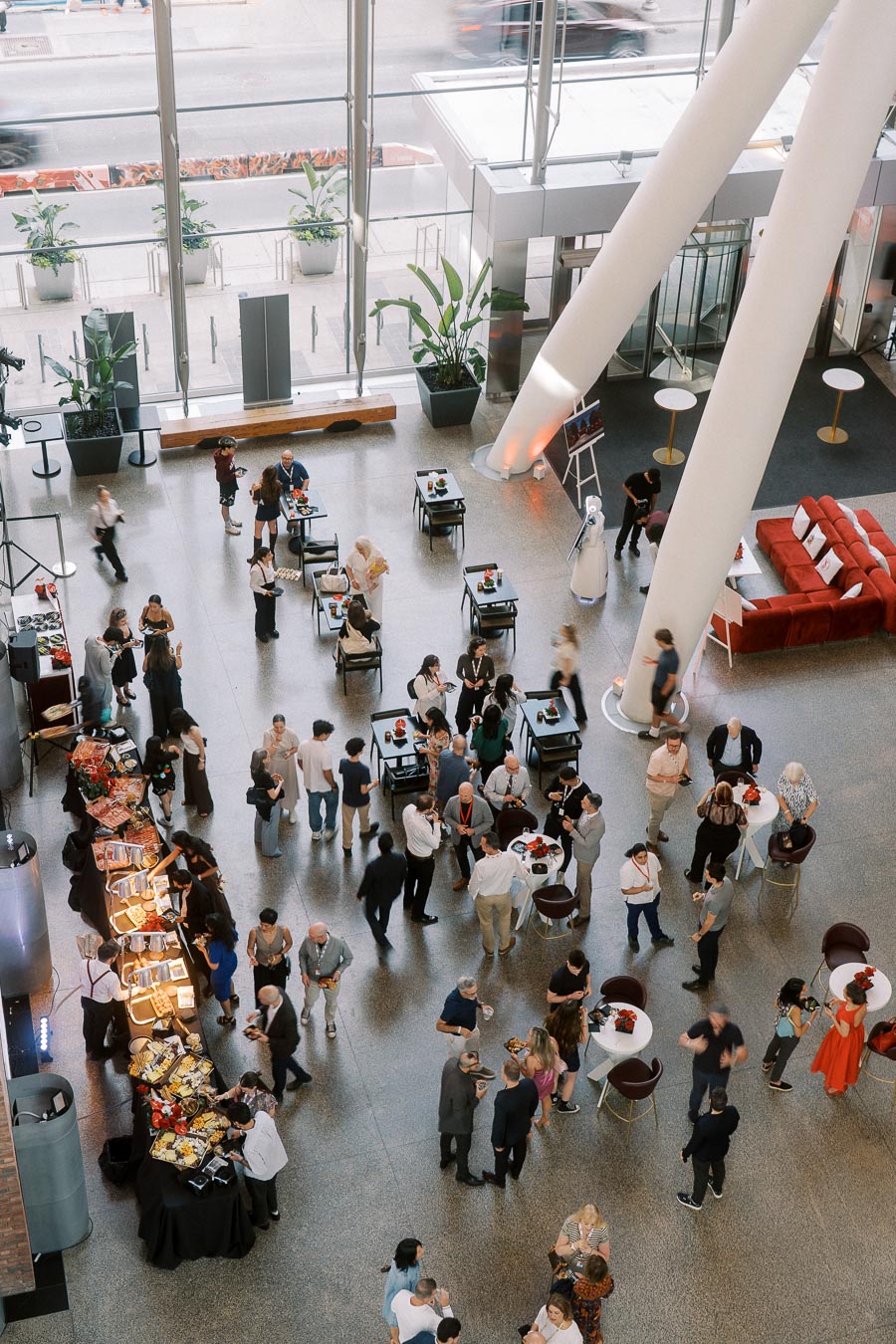 Aerial view of guests mingling, networking, and enjoying catered food in the bright, modern glass atrium at Ricarda’s during the Toronto Prep Forever Launch Party.