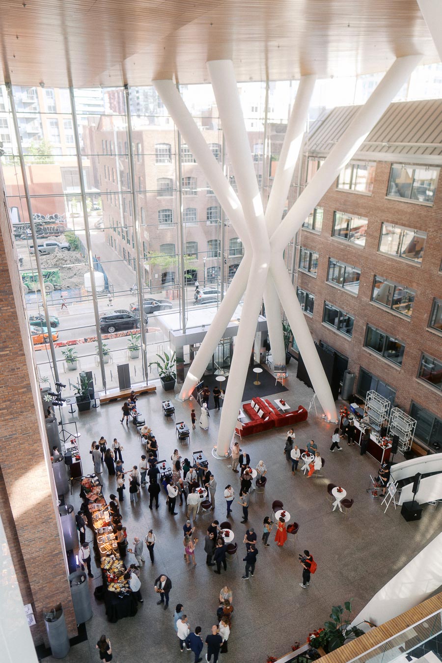 Overhead view of guests mingling in the modern glass atrium of Ricarda’s, Toronto, during the Toronto Prep School launch event, with visible catering tables and lounge areas.