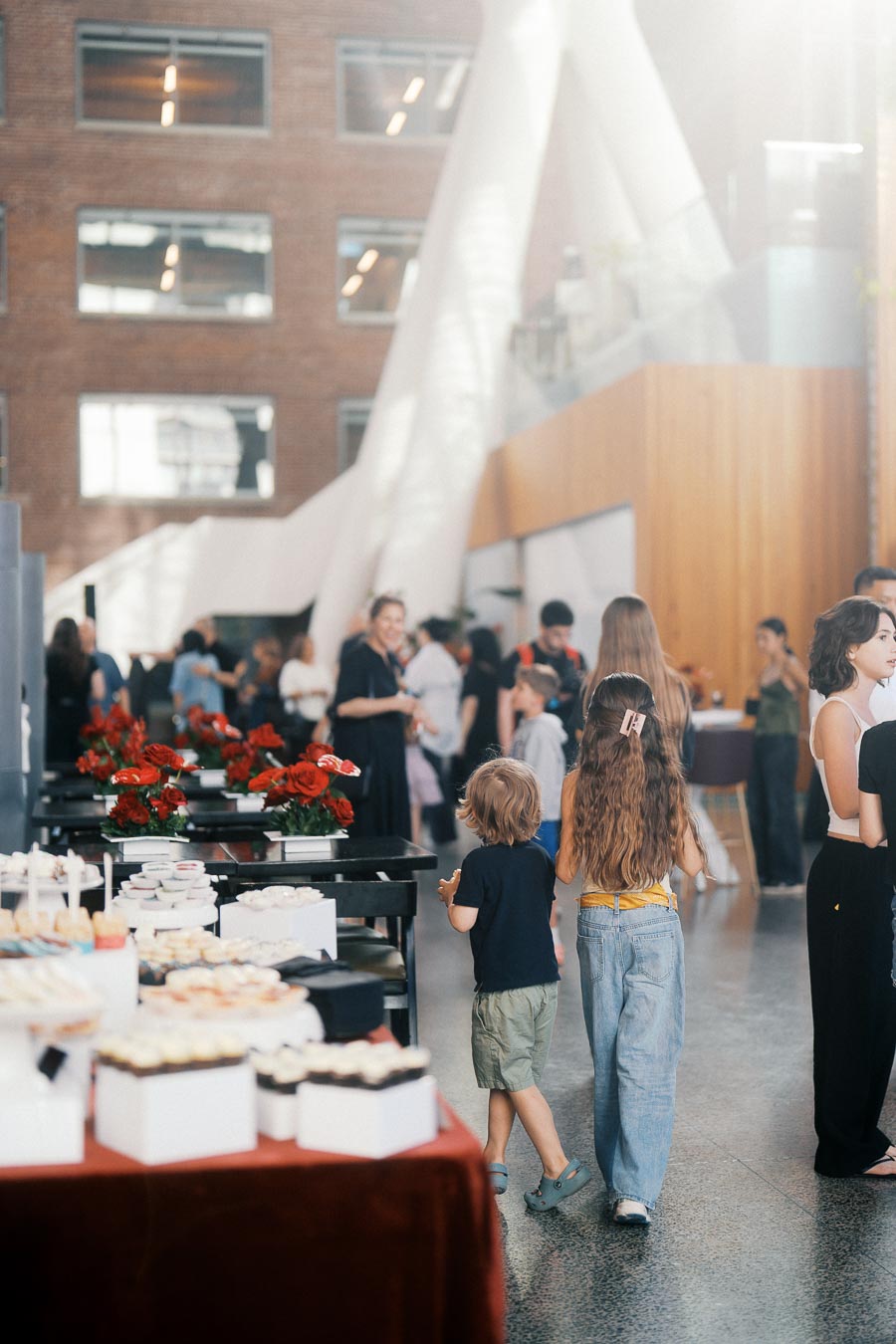 Children and adults gather near dessert tables with red floral arrangements at The Atrium at Ricarda’s during the Toronto Prep Forever Launch Party, June 2026.