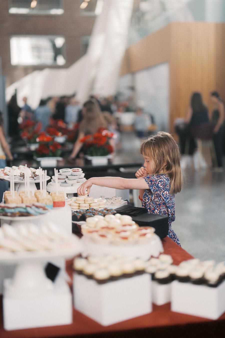 A young girl in a patterned dress reaches for desserts on a table at the Toronto Prep Forever Launch Party at The Atrium at Ricarda’s, Toronto.
