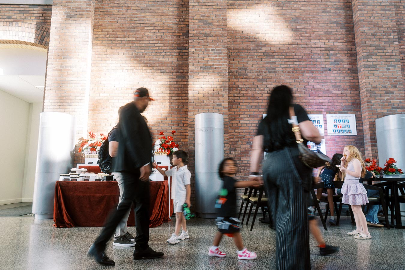 Guests and children walk past a decorated table and mingle in the brick-walled atrium at Ricarda’s during the Toronto Prep Forever Launch Party.