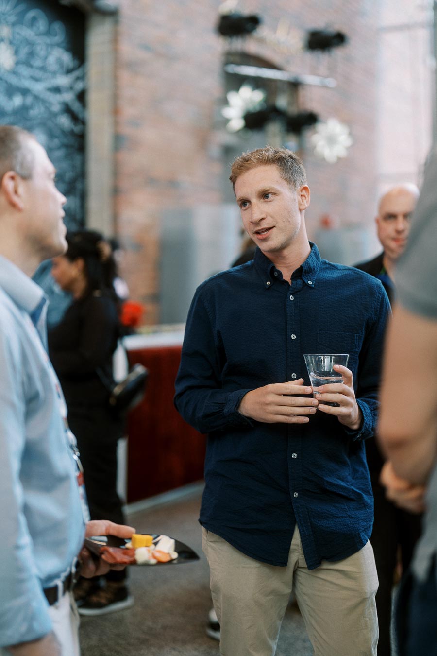 Two guests engaged in conversation at the Toronto Prep Forever Launch Party, one holding a drink and another with a plate of appetizers, at Ricarda’s in Toronto.
