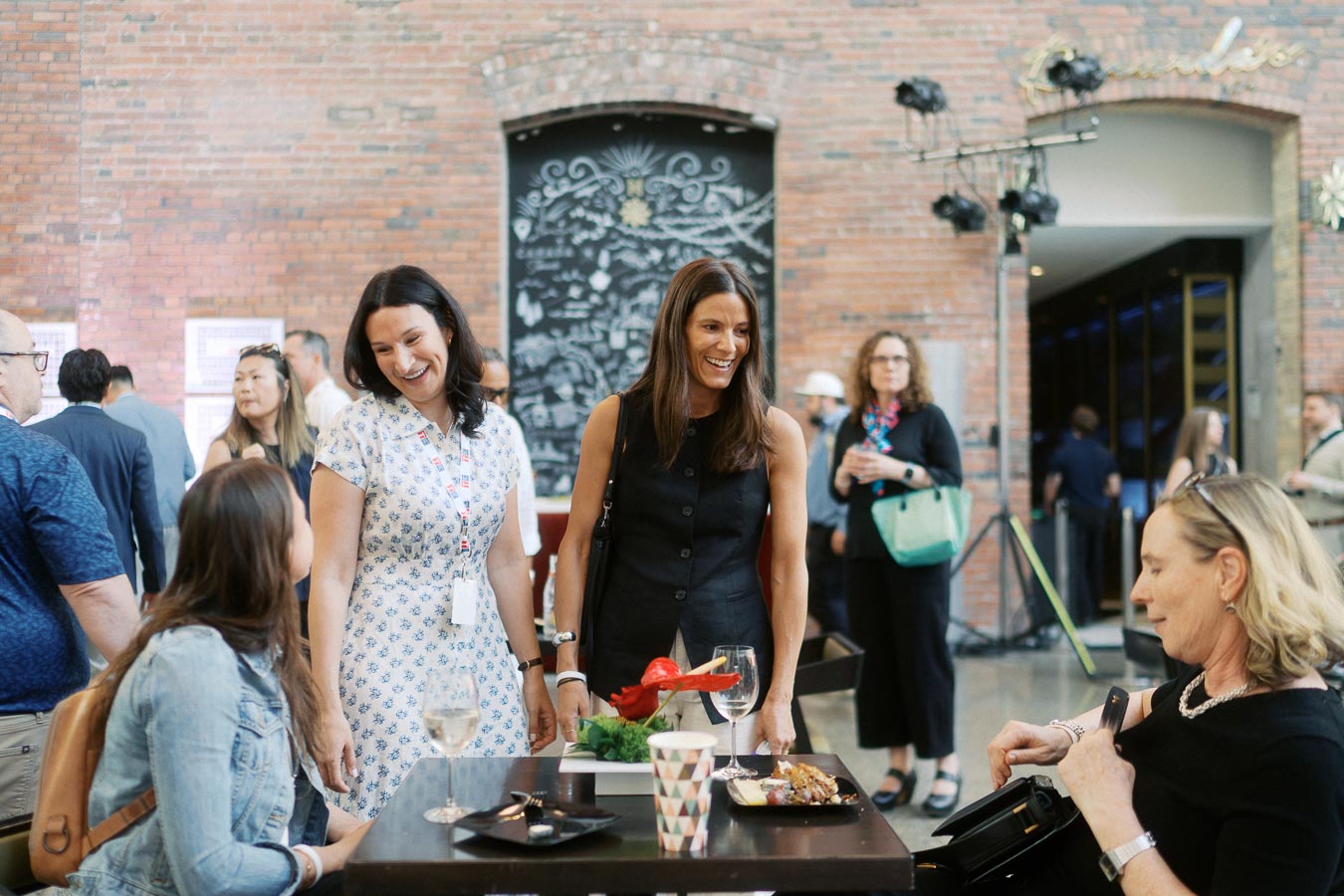 A group of women engaged in conversation around a table with drinks and food at Ricarda's in Toronto during the Toronto Prep Forever Launch Party.