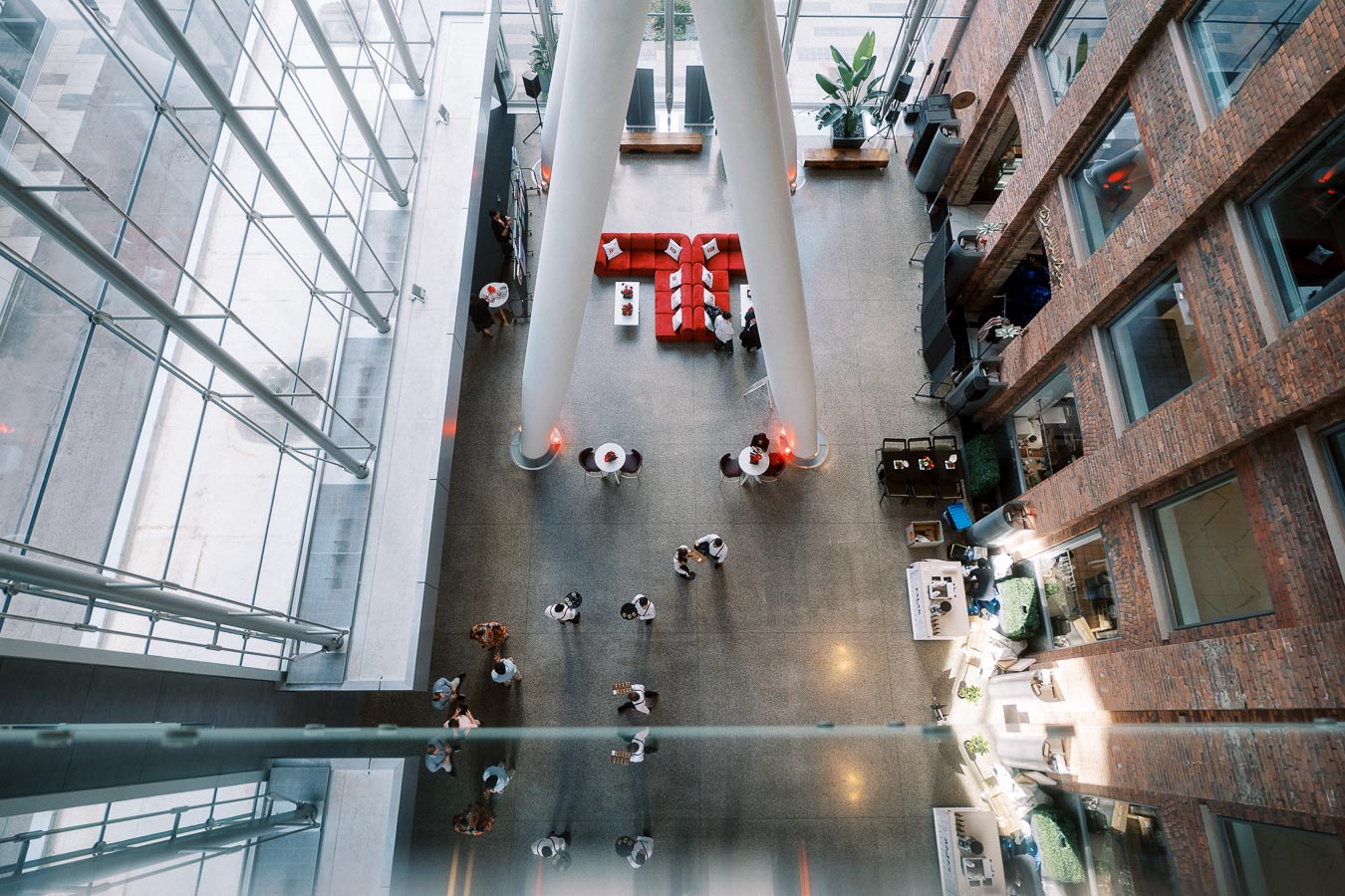 Overhead view of The Atrium at Ricarda’s, Toronto, showing guests, lounge seating, brick walls, and glass ceiling during a school launch event.