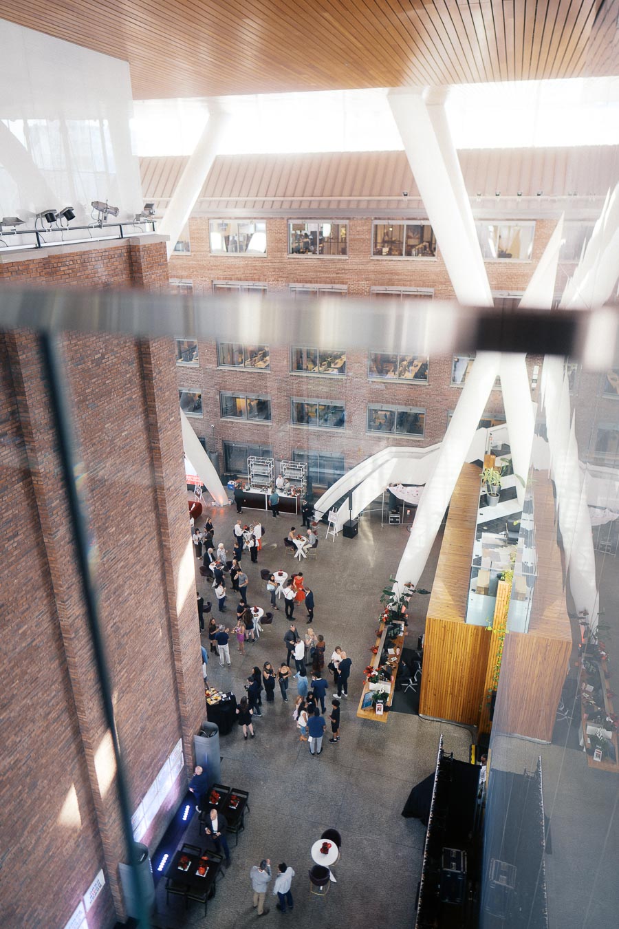 Aerial view of guests networking in the atrium at Ricarda’s, Toronto, with modern brick and glass architecture during a school launch event.
