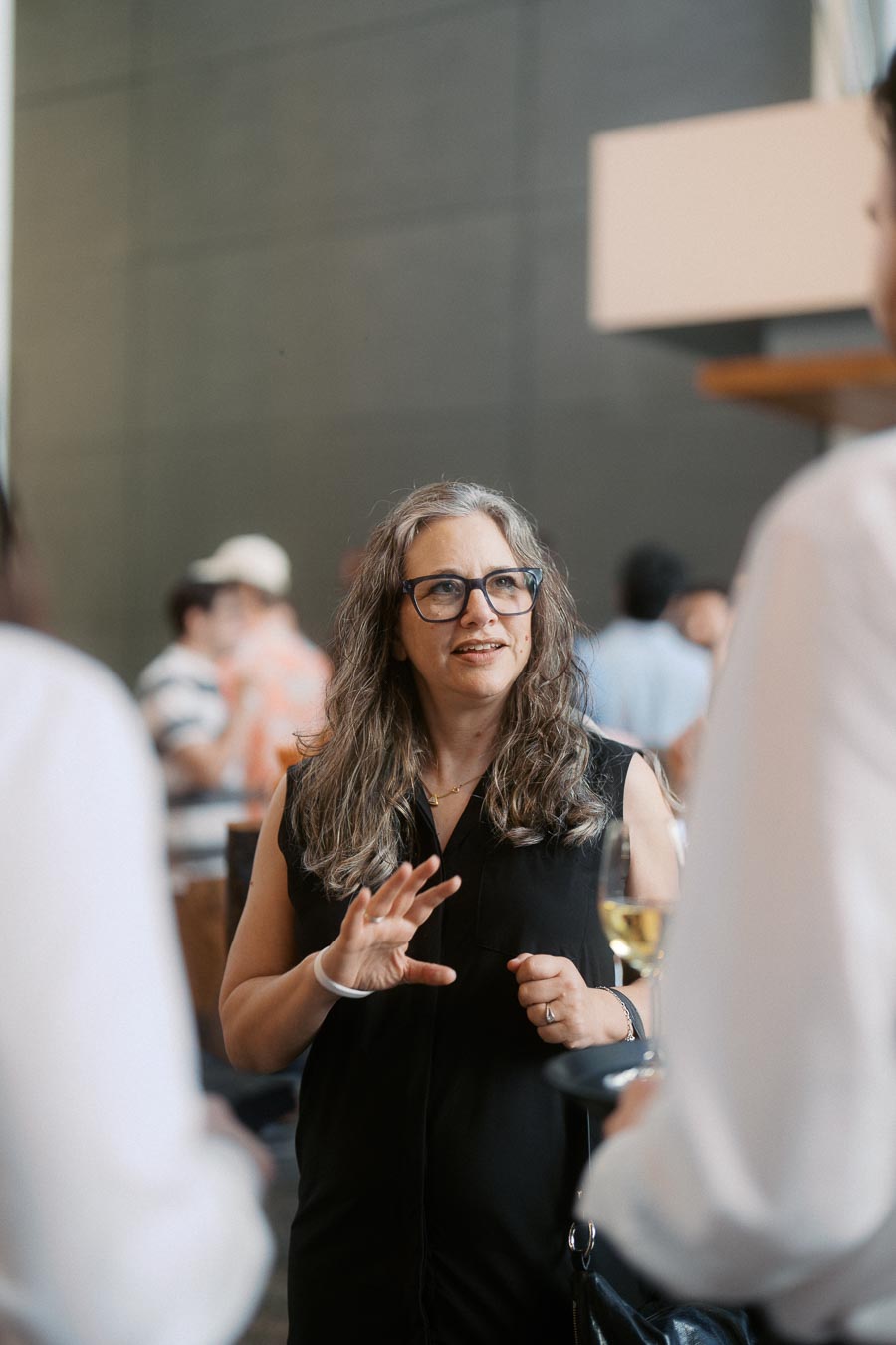 A woman with long hair and glasses converses with two people at the Toronto Prep Forever Launch Party at Ricarda’s in Toronto.