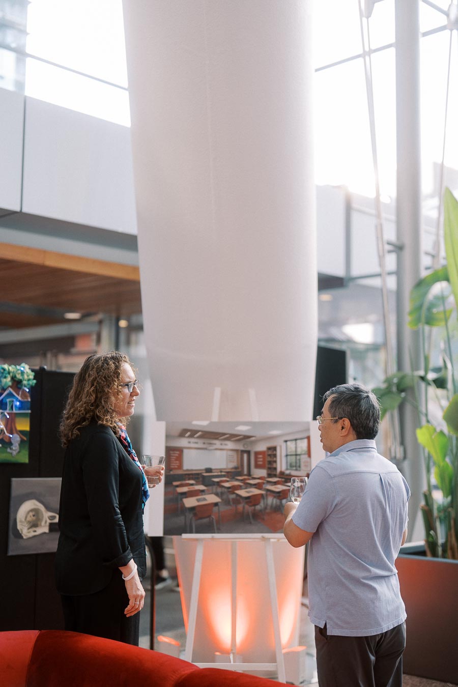 Two adults stand and talk in front of a rendering of a classroom at the Toronto Prep Forever Launch Party inside Ricarda’s Atrium, Toronto.