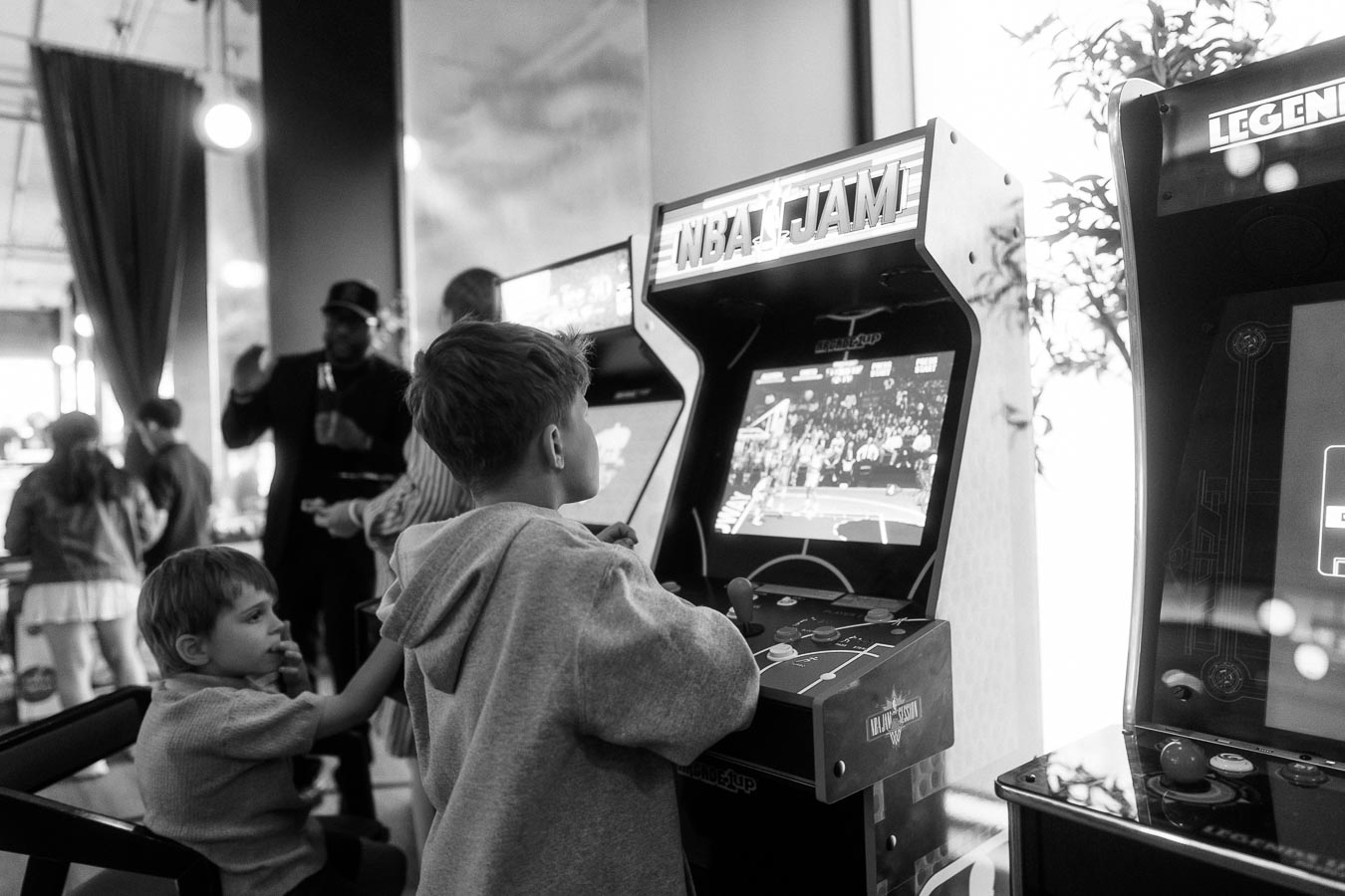 Children playing NBA Jam arcade game in the kids lounge during the Toronto Prep Forever Launch Party at Ricarda’s in Toronto, with other guests in the background.