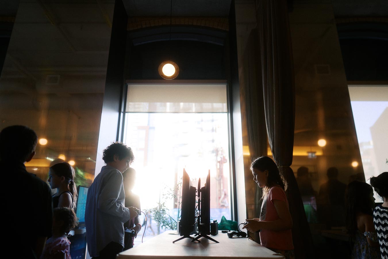 Children playing video games at a central table inside The Atrium at Ricarda’s during the Toronto Prep Forever Launch Party, with natural light streaming through large windows.