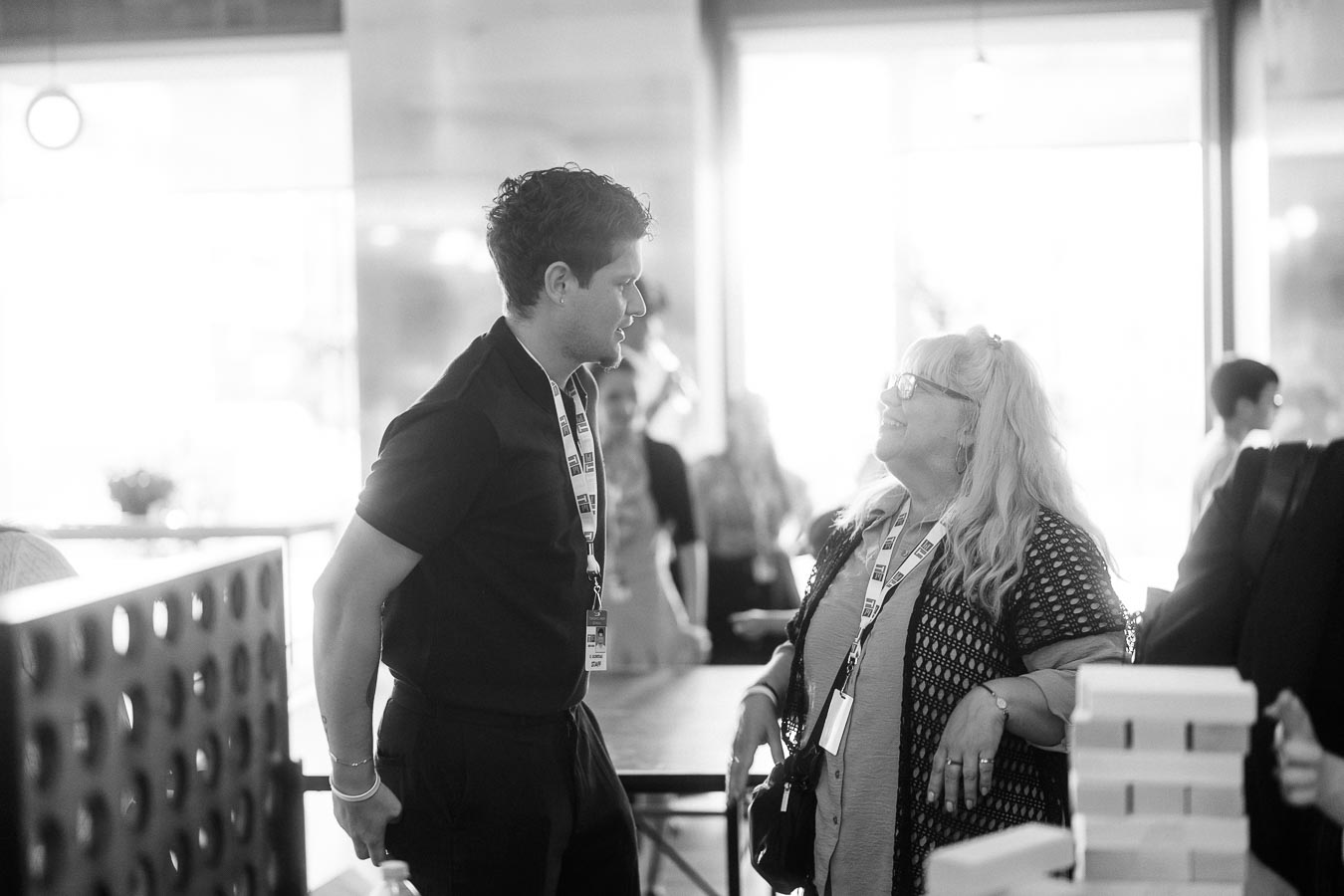 Two guests wearing event lanyards converse and smile at the Toronto Prep Forever Launch Party at Ricarda’s in Toronto, with a blurred background of attendees.