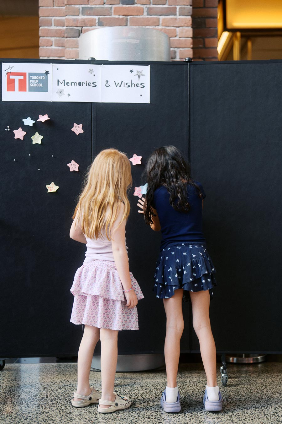 Two young girls stand at a Memories &amp; Wishes wall, posting star-shaped notes during the Toronto Prep School Forever Launch Party at Ricarda’s in Toronto.