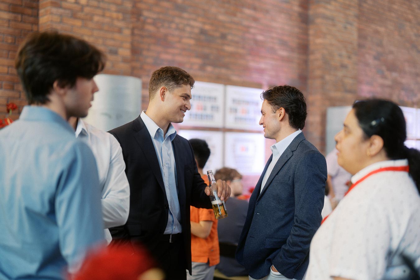 A group of adults and young people converse in a modern atrium with brick walls during the Toronto Prep Forever Launch Party at Ricarda’s in Toronto.
